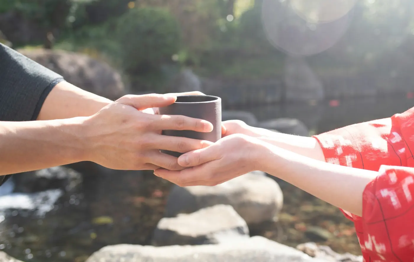 One person gently passing a warm cup to another